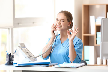 Young medical assistant talking by phone in clinic