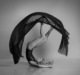 Flexible girl posing with black flying cloth