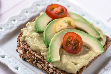 Organic Guacamole Avocado Spread and Slices with Fresh Cherry Tomato and Black Sesame. Healthy Diet Breakfast Concept.