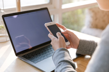 Young women working on her laptop and smart phone, Women hands using smart phone in the office.