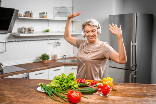 Mature Woman Dancing While Cooking In Kitchen