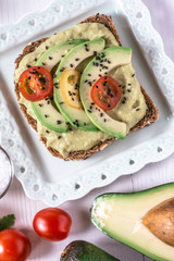 Organic Guacamole Avocado Spread and Slices with Fresh Cherry Tomato and Black Sesame. Healthy Diet Breakfast Concept.
