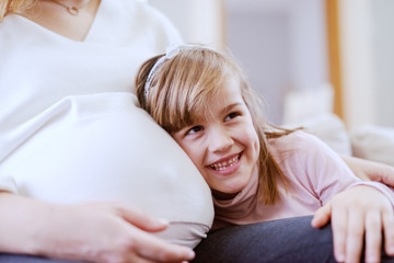 Obraz na płótnie Canvas Cute smiling Caucasian girl listening to unborn baby's heartbeats.