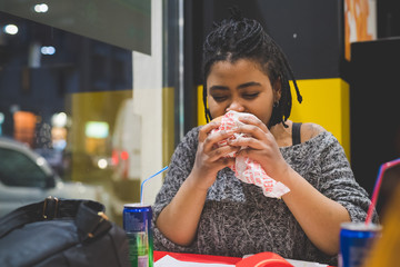 young african woman eating sandwich indoor