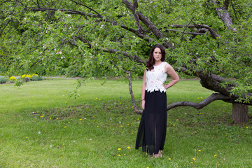Horizontal shot of beautiful brunette young woman in white top and long slitted black skirt...
