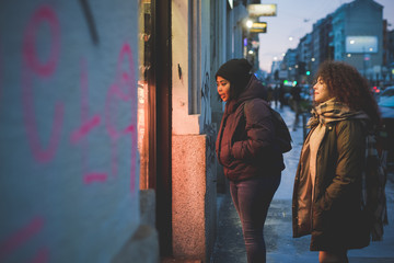 Obraz na płótnie Canvas two multiracial girlfriends looking shop windows in the street