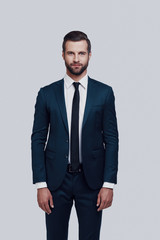 Portrait of confidence. Handsome young man looking at camera while standing against grey background