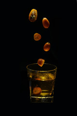glass of whiskey and candle on black background