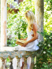 The girl in the old gazebo in the garden reads a book. Retro vintage style