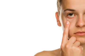 Young woman pulling her lower eyelid with her finger on white background