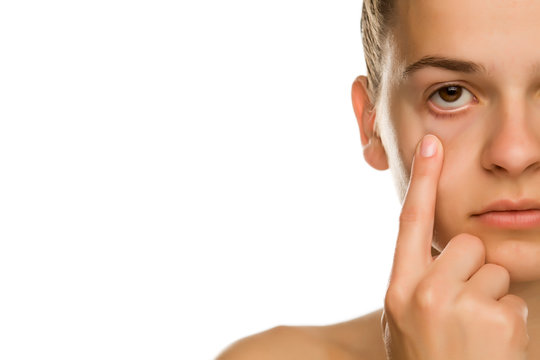 Young Woman Pulling Her Lower Eyelid With Her Finger On White Background