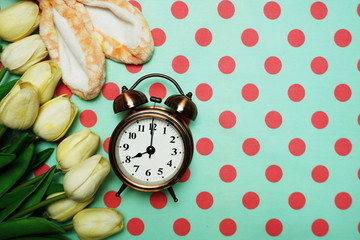 Rabbit ears and Alarm clock with tulip flower bouquet on green polka dot background