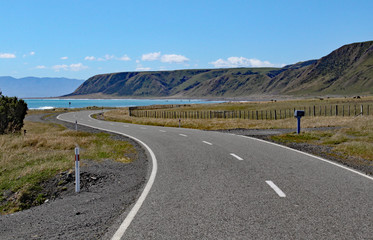 A deserted road winds towards the bay at Cape Palliser, North, Island, New Zealand