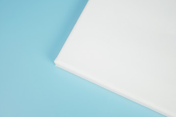 Primed white canvas on stretcher, mock up poster. Corner of blank canvas on blue background.