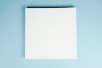Mock-up poster. Blank square canvas on stretcher on blue wall.