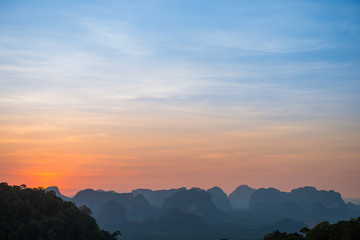 Landscape with beautiful dramatic sunset and silhouette of blue mountains at horizon, Thailand