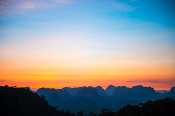 Landscape with beautiful dramatic sunset and silhouette of blue mountains at horizon, Thailand
