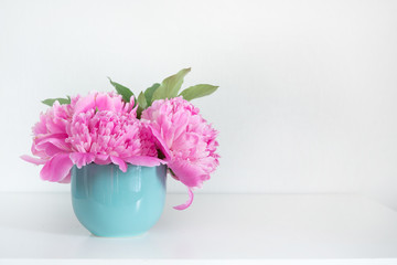 Bouquet of pink peony in blue vase on white. Copy space for text. Mothers day.