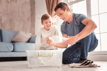 Modern father wearing jeans telling his son about plastic