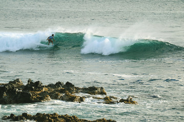 Young man surfing on the breaking waves in Pacific Ocean at Hanga Roa, Easter Island, Chile, South America