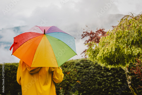 Back View Of Girl In Yellow Raincoat With Colorful Rainbow