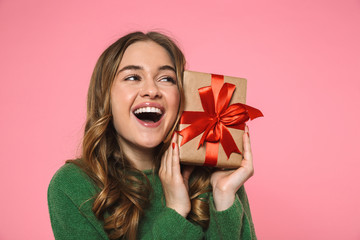 Cheerful blonde woman wearing in green sweater holding gift box
