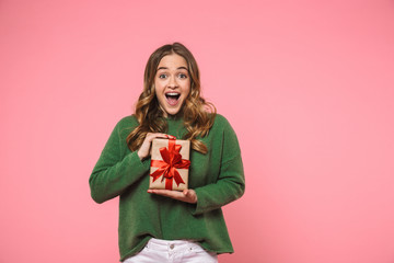 Surprised cheerful blonde woman wearing in green sweater holding gift