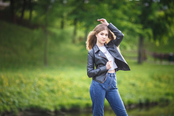 portrait of little beautiful stylish kid girl in city park on green forest background