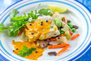 Plate of Steamed fish with curry sauce with salad
