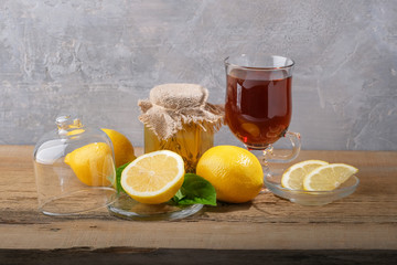 Fresh lemons, a jar of honey and a glass of tea on the table.