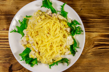 Festive salad with chicken breast, sweet corn, canned pineapple, cheese and mayonnaise on wooden table
