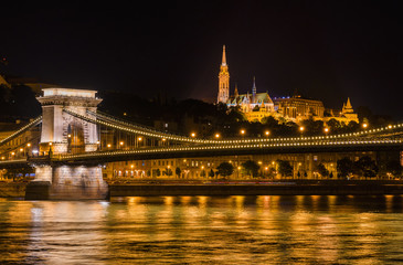 Budapest by night. View of Danube in the center of Budapest with the iconic and monumental Chain Bridge, St Matthias Church and Fisherman's Bastion at the top of Castle Hill