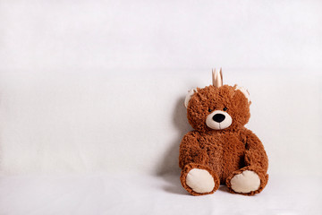 Children's toys - bears of brown and beige color with golden little crownsс are sitting on the sofa. Selective focus.