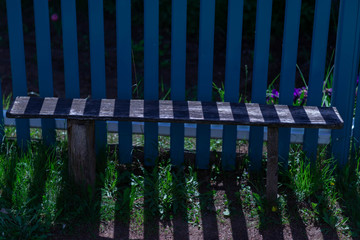 blue fence,bench and striped shade on a Sunny summer day
