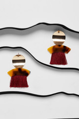 Shot of long earrings, adorned with massive pendants and wine red tassels. The accessory set is...