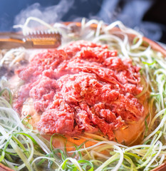 Beef barbecue bulgogi in Korean restaurant in Seoul, lifestyle fresh korean food cuisine on copper pan with sliced green onion, close up, copy space