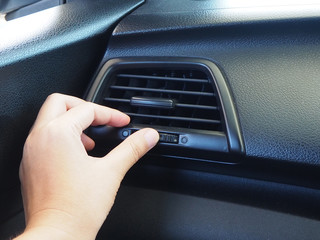 Woman hand using control car air conditioning system grid panel on console
