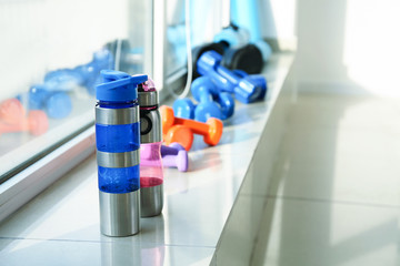 Bottles of water and dumbbells on window sill in gym
