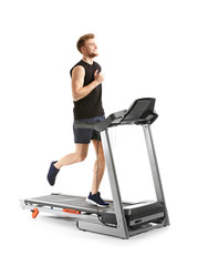 Sporty young man training on treadmill against white background