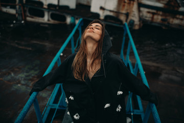 Fototapeta premium Woman posing on bridge against the background of an old rusty ship.