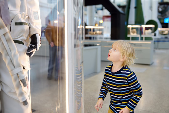 Little caucasian boy looking astronaut space suit in museum