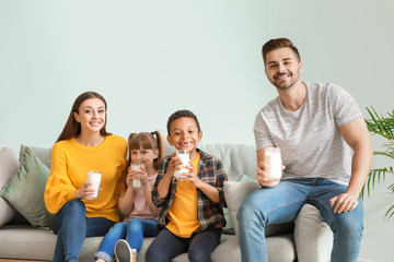 Young family with glasses of tasty milk at home