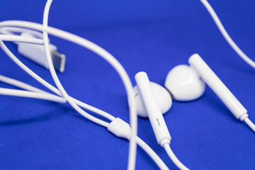 White earphones with connector on blue background - Image