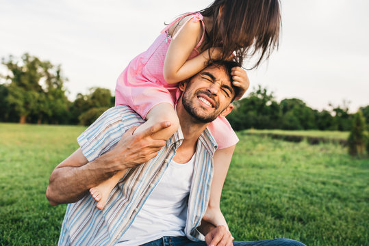 Outdoor image of funny dad spending good time together with his pretty daughter. Happy cute little girl playing with father in the park. Happy Father's Day. Daddy and daughter shares love. Fatherhood