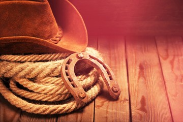 Old horseshoe , lariat lasso and cowboy hat on background