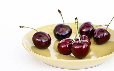 ripe garden's sweet cherry on a yellow plate