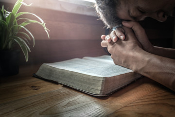 focus at beside of old Bible with man praying on Bible background.