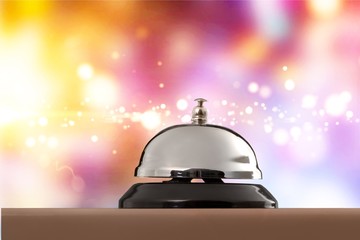 Vintage hotel reception service desk bell on wooden table with abstract background