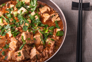 Traditional Chinese dish tofu with minced meat and tofu cheese in a bowl on a linen rustic napkin, close-up