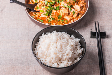 Traditional Chinese Sichuan cuisine - a bowl of rice and mapo tofu in a large plate on a rustic table